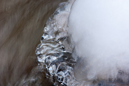 Streaming water in a small river at early springtime. Spring scene.  Mountain landscape with a frozen creekの写真素材