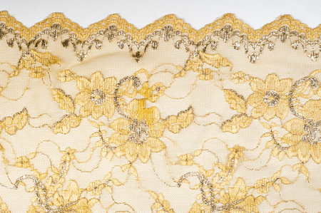 Texture. Lace fabric golden yellow color photos made in the studio. a fine open fabric, typically one of cotton or silk, made by looping, twisting, or knitting thread in patterns and used especially for trimming garments.の写真素材