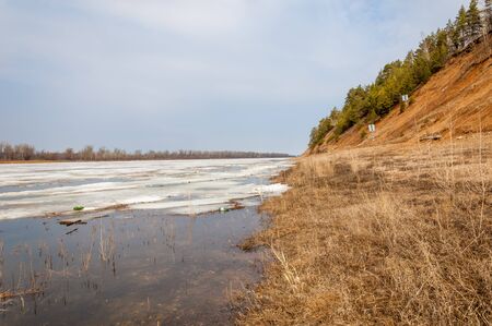 Spring River, the ice on the river. picturesque spring landscape with river ice melted bare trees and beautiful clouds in the blue skyの写真素材