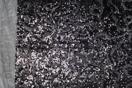 The texture of the fabric is black with sequins. a small, shiny disk sewn as one of many onto clothing for decoration.の写真素材