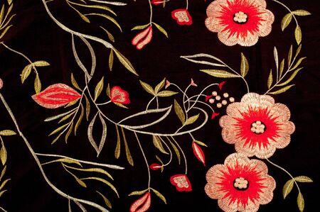 Silk fabric texture dark brown with bright floral pattern. Fragment of colorful retro tapestry...