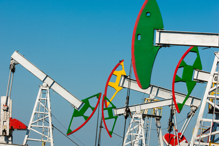 Oil rocking chair closeup. Oil rocking chair on a background of blue sky. The pumping unit as the oil pump installed on a well. Equipment of oil fields.の写真素材