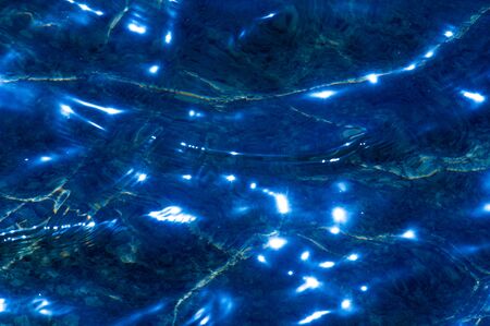 Texture background. Background. The water in the pool is photographed in counter light. The glare...
