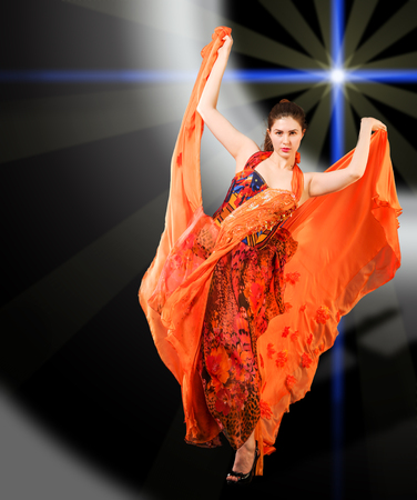 Beautiful girl, beautiful red dress, developed in the wind, beautiful light. frozen dynamics. Woman in red blowing flying red dress dissolving in splashの写真素材