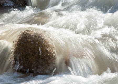 Streaming water in a small river at early springtime. Spring scene.  Mountain landscape with a frozen creekの写真素材