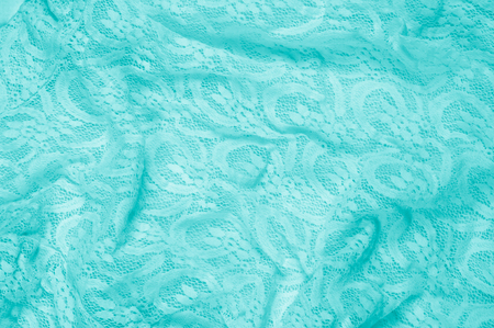 Texture, fabric, background. Lacy turquoise fabric, lace. A thin open fabric, usually cotton or silk, made by a loop, twisting or knitting on patterns and is used specially for trimming clothes.の写真素材