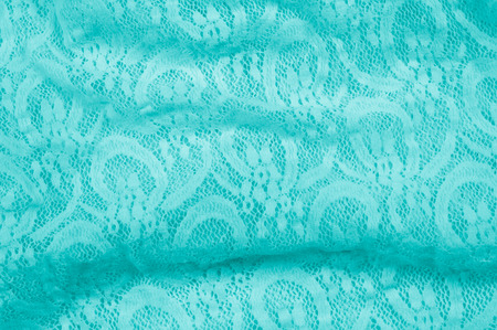 Texture, fabric, background. Lacy turquoise fabric, lace. A thin open fabric, usually cotton or silk, made by a loop, twisting or knitting on patterns and is used specially for trimming clothes.の写真素材