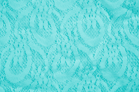 Texture, fabric, background. Lacy turquoise fabric, lace. A thin open fabric, usually cotton or silk, made by a loop, twisting or knitting on patterns and is used specially for trimming clothes.の写真素材