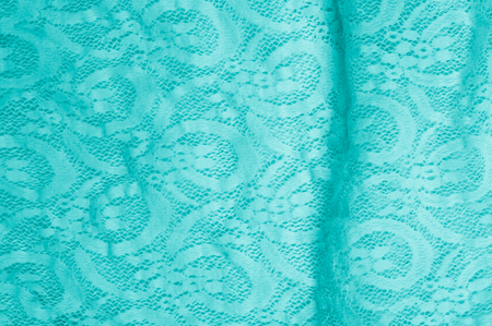Texture, fabric, background. Lacy turquoise fabric, lace. A thin open fabric, usually cotton or silk, made by a loop, twisting or knitting on patterns and is used specially for trimming clothes.の写真素材