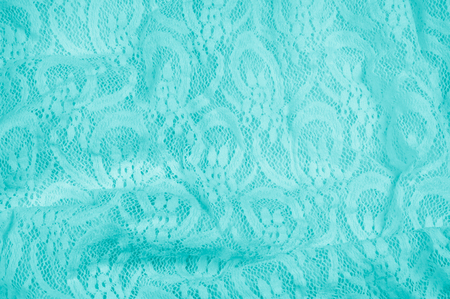 Texture, fabric, background. Lacy turquoise fabric, lace. A thin open fabric, usually cotton or silk, made by a loop, twisting or knitting on patterns and is used specially for trimming clothes.の写真素材