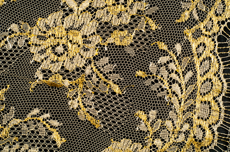 Image texture background, decorative gold lace with pattern. Golden vintage lacy background. Golden lace on a black background. Spandex, macro. Lacy decorative floral pattern.の写真素材