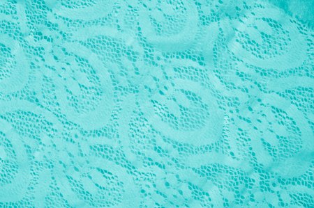 Texture, fabric, background. Lacy turquoise fabric, lace. A thin open fabric, usually cotton or silk, made by a loop, twisting or knitting on patterns and is used specially for trimming clothes.の写真素材