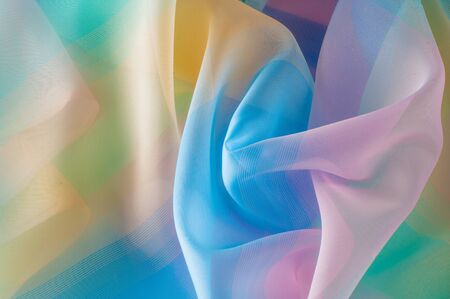 Texture, background, pattern. Silk fabric is transparent, yellow-pink green in blue. Abstract soft...