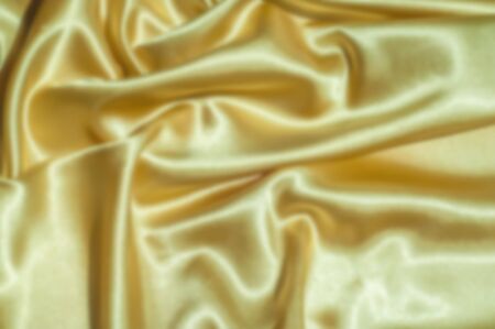 The blur is gaussian for designers. Texture, fabric, background. Abstract background of luxurious fabric or liquid waves or wavy grunge crease silk satin texture. goldの写真素材