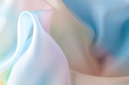 Texture, background, pattern. Silk fabric is transparent, yellow-pink green in blue. Abstract soft chiffon texture background.の写真素材