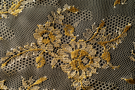 Image texture background, decorative gold lace with pattern. Golden vintage lacy background. Golden lace on a black background. Spandex, macro. Lacy decorative floral pattern.の写真素材
