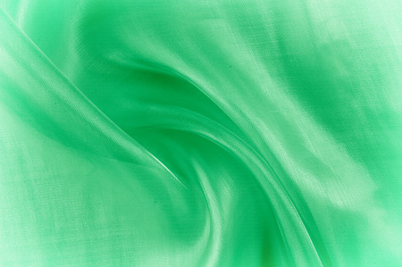 Background texture, pattern. Green silk background with some soft folds and highlights. green background abstract cloth or liquid wave illustration of wavy folds of silk texture satinの写真素材