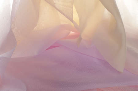 Texture, background, pattern. Silk transparent fabric. Blue yellow pink shades. of a color intermediate between red and white, as of coral or salmon.の写真素材