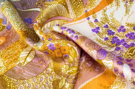 Texture, background, pattern. Blue silk fabric, yellow flowers. Silk scarf with flowering flowers in...