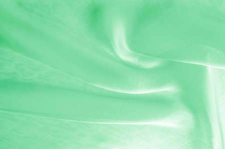 Background texture, pattern. Green silk background with some soft folds and highlights. green background abstract cloth or liquid wave illustration of wavy folds of silk texture satinの写真素材
