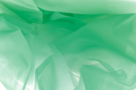 Texture, background, pattern. The texture of the silk fabric is green. Silk fabric is transparent. Fabric or liquid wave illustration of wavy creases of silk satin texture or velvet materialの写真素材