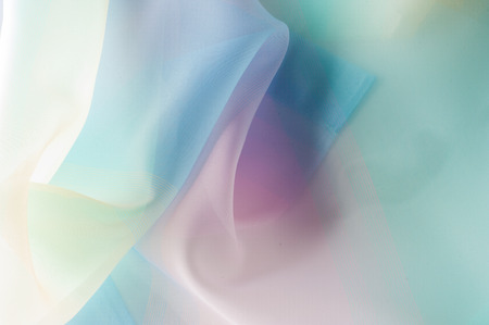 Texture, background, pattern. Silk fabric is transparent, yellow-pink green in blue. Abstract soft chiffon texture background.の写真素材
