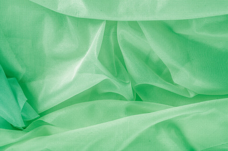 Texture, background, pattern. The texture of the silk fabric is green. Silk fabric is transparent. Fabric or liquid wave illustration of wavy creases of silk satin texture or velvet materialの写真素材
