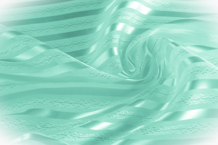 Background texture, pattern. Green silk fabric with a light stripe. Green cloth. Smooth elegant...