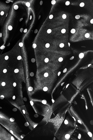 Texture, background, pattern. Girl's skirt. Silk fabric on a black background white polka dotsの写真素材