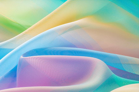 Texture, background, pattern. Silk fabric is transparent, yellow-pink green in blue. Abstract soft chiffon texture background.の写真素材