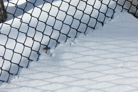Winter landscape. texture background. reflection of shadows on the snow from the artificial fenceの写真素材
