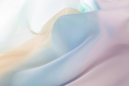 Texture, background, pattern. Silk fabric is transparent, yellow-pink green in blue. Abstract soft chiffon texture background.の写真素材