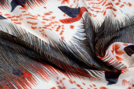Texture, background, pattern. Women's woolen scarf. White, red, brown, black. Abstract pattern.