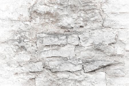 Texture, background, pattern. An old cement stone wall as vintage cracked, worn and worn out creative poster design. Cracks, scrapes, peeling old paint and plaster on the background of old cement wallの写真素材