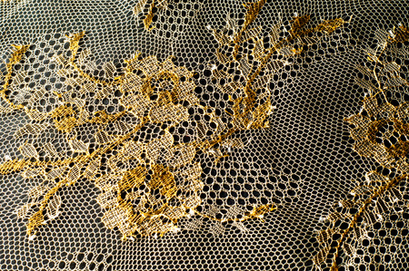 Image texture background, decorative gold lace with pattern. Golden vintage lacy background. Golden lace on a black background. Spandex, macro. Lacy decorative floral pattern.の写真素材