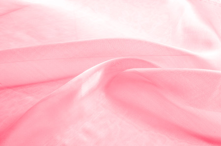 Background texture, pattern. Cloth pink silk. Smooth elegant pink silk or satin can use as wedding background. Luxurious valentine day background design.の写真素材