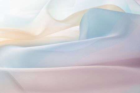 Texture, background, pattern. Silk fabric is transparent, yellow-pink green in blue. Abstract soft...