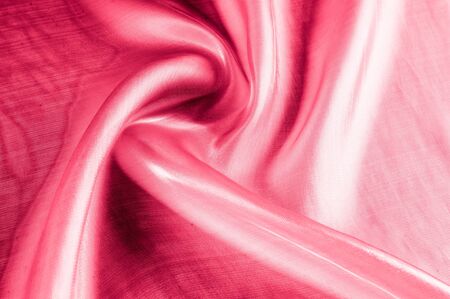 Background texture, pattern. Cloth pink silk. Smooth elegant pink silk or satin can use as wedding background. Luxurious valentine day background design.の写真素材