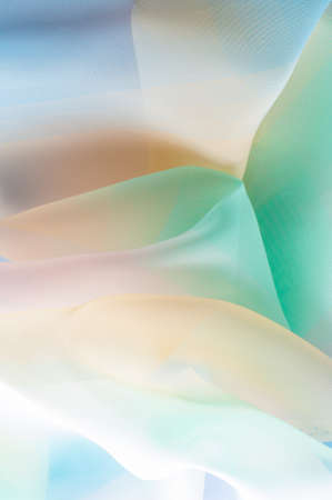 Texture, background, pattern. Silk fabric is transparent, yellow-pink green in blue. Abstract soft chiffon texture background. の写真素材