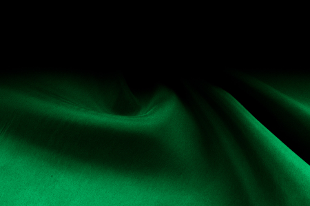 Background texture, pattern. Thick thick silk fabric is green. This satin fabric is ideal for creating a smooth flow in design, it has a liquid drape and exquisite shine.の写真素材