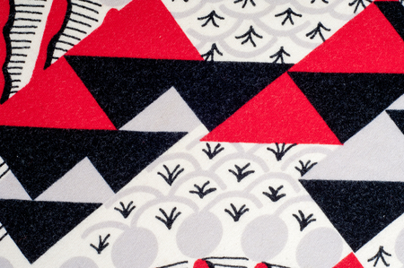 Texture, background, pattern. Knitted fabric of abstract design. Red white black rhombuses