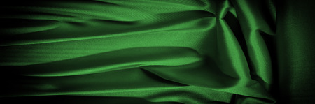 Texture, background, pattern. Fabric silk is dark green. Expressing harmony, global appeal, The combination of green and black, color purple contains passion, strength and energy. Green color,の写真素材
