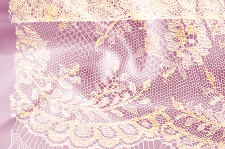 Image texture background, decorative gold lace with pattern. Golden vintage lacy background. Gold lace on a pink background. Spandex, macro. Lacy decorative floral pattern.の写真素材