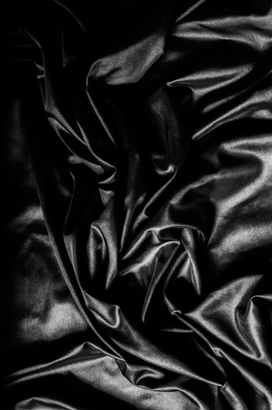 Texture, background, pattern. Black silk fabric. Fabric silk elastane satin black flowing stretch nobleの写真素材