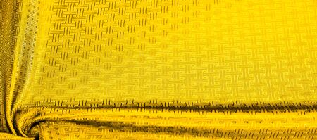 Background texture, pattern. Yellow, mustard silk fabric with a small checkered pattern. Muffled...
