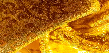 Texture background, pattern. fabric; yellow gold brocade. Organza brocade fabric - shepherd, with a crunchy palm. It has a large yarn-dyed flower embroidered pattern throughout.の写真素材