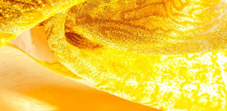 Texture background, pattern. fabric; yellow gold brocade. Organza brocade fabric - shepherd, with a crunchy palm. It has a large yarn-dyed flower embroidered pattern throughout.の写真素材