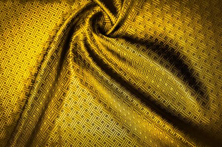 Background texture, pattern. Yellow, mustard silk fabric with a small checkered pattern. Muffled yellow braided with subtitles with sparkles - a bright chart-plot design. Individual pieces.の写真素材