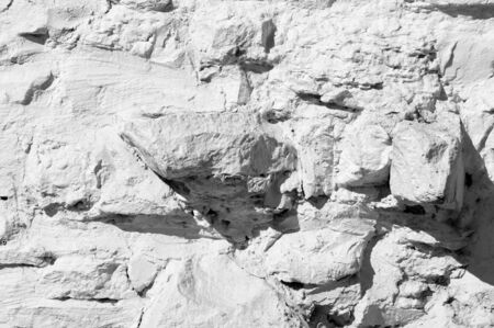 Texture background, pattern. The wall is lined with granite stones and whitewashed with lime. a continuous vertical brick or stone structure that encloses or divides an area of land.の写真素材