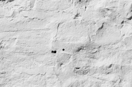 Texture background, pattern. The wall is lined with granite stones and whitewashed with lime. a continuous vertical brick or stone structure that encloses or divides an area of land.の写真素材